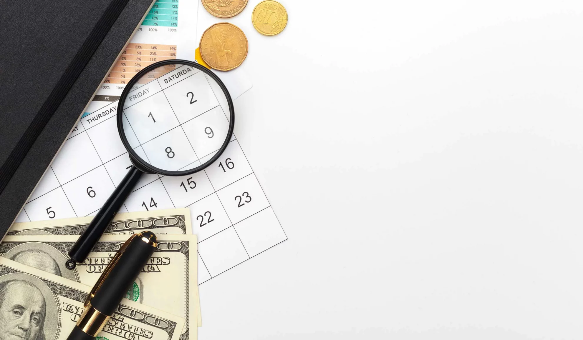 money magnifying glass and calendar on white table